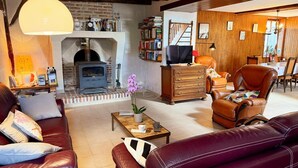 A cozy living room with a fireplace, leather sofas, a coffee table, and a bookshelf.