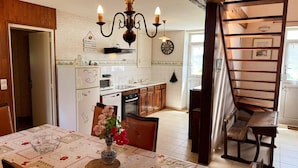 A kitchen with a dining table, chairs, a chandelier, and a staircase.