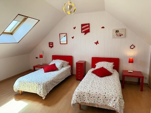 A bedroom with two beds, a skylight, and decorative wall stickers.