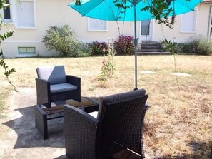 An outdoor seating area with wicker furniture and a blue umbrella. - Charming Cottage with Private Yard, Near Loire Castles and Cycling Routes (Muides-sur-Loire)