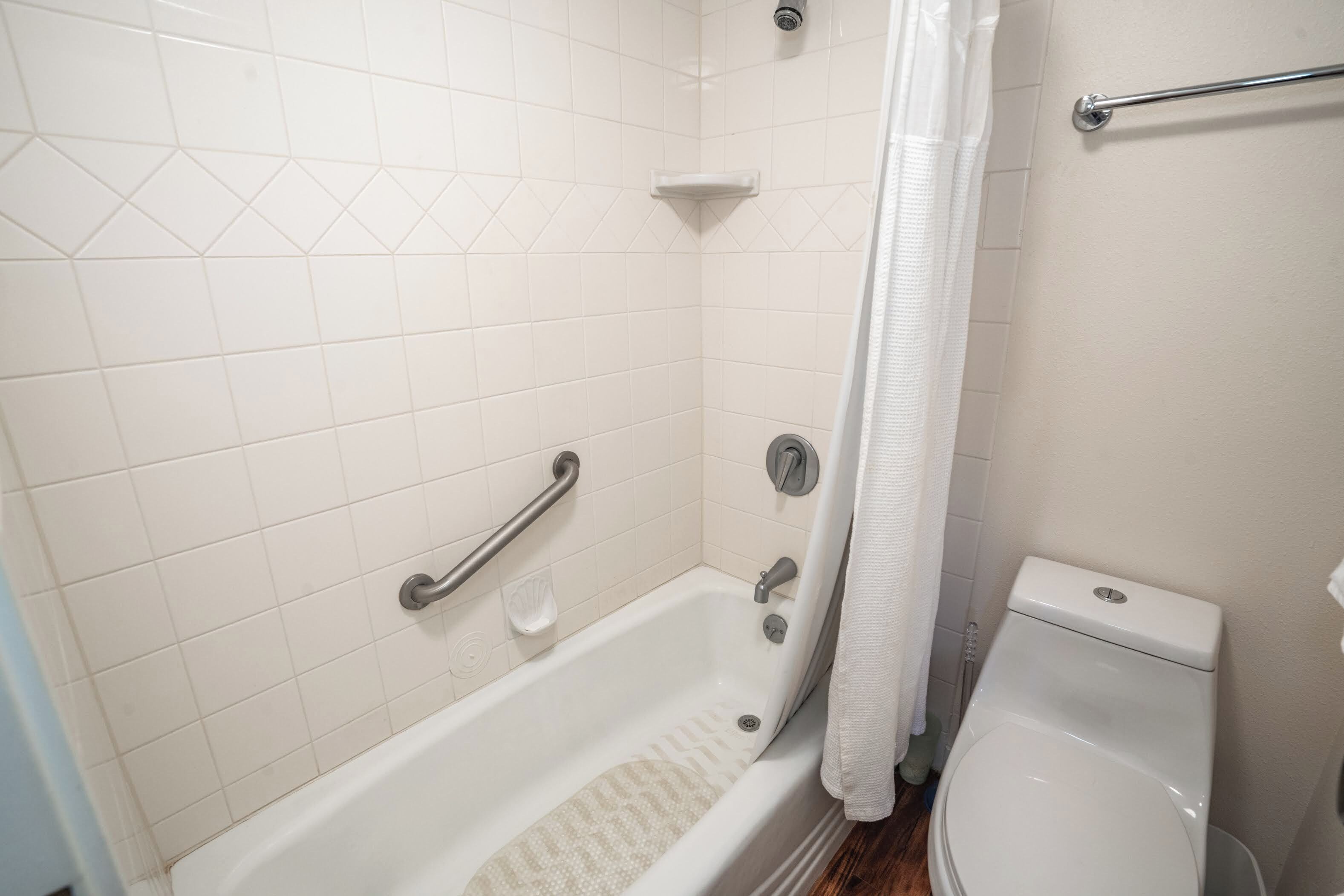 A bathroom with a bathtub, toilet, and shower curtain.