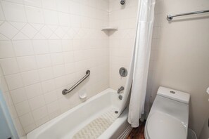 A bathroom with a bathtub, toilet, and shower curtain.