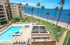 A hotel with a swimming pool, sun loungers, and a view of the beach and ocean.