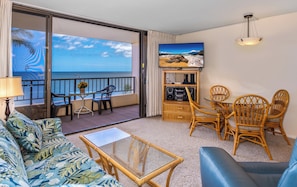A balcony with a view of the sea, a sofa, a table, and wicker chairs.