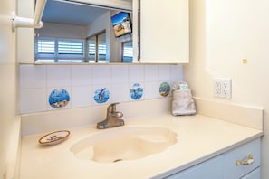 A bathroom with a sink, mirror, and decorative tiles.