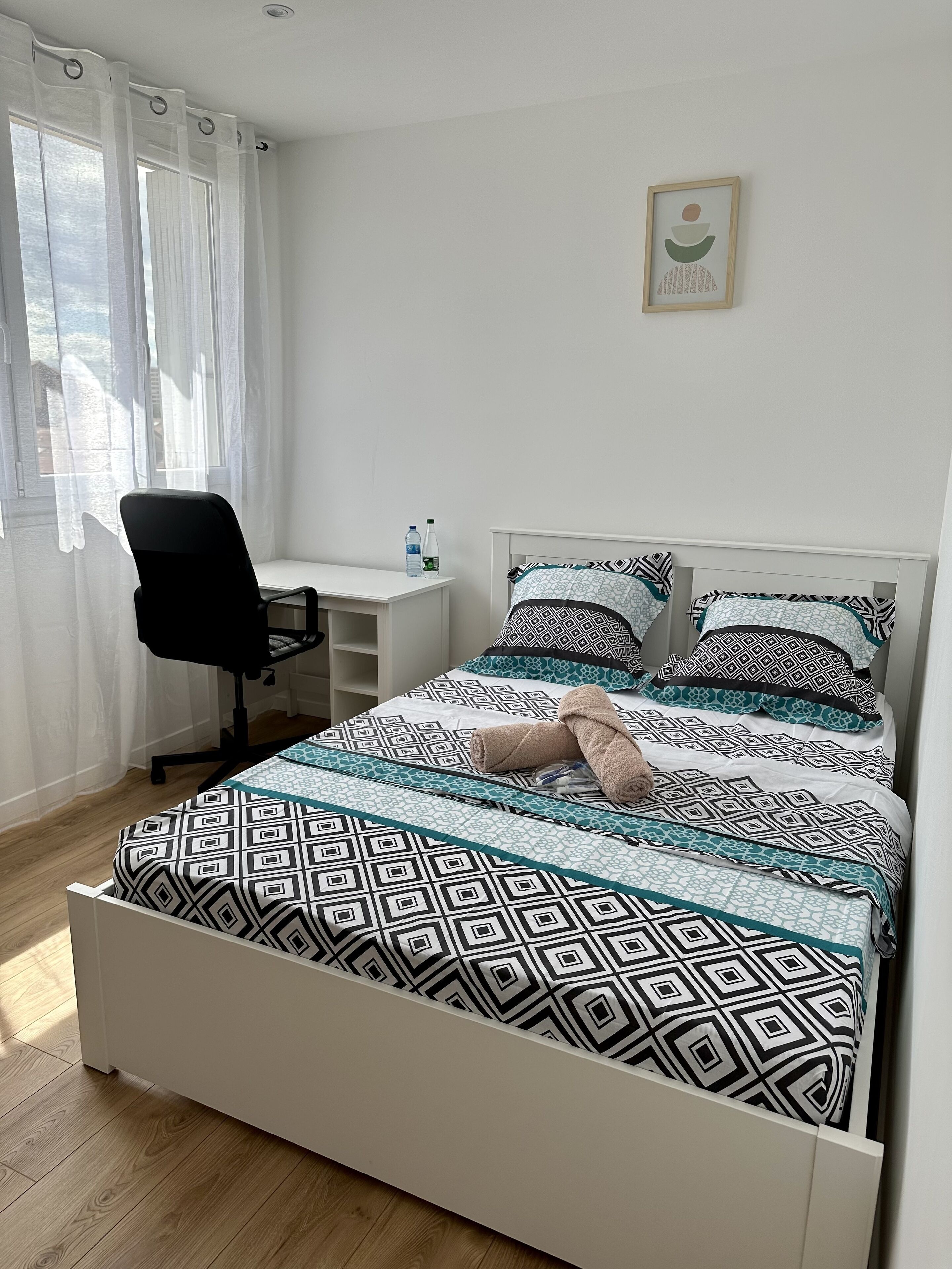 A bedroom with a bed, a desk, and a chair.