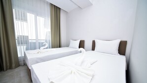 A hotel room with two beds, a large window with curtains, and a view of the outdoors. - Alkan Apart (Demre)