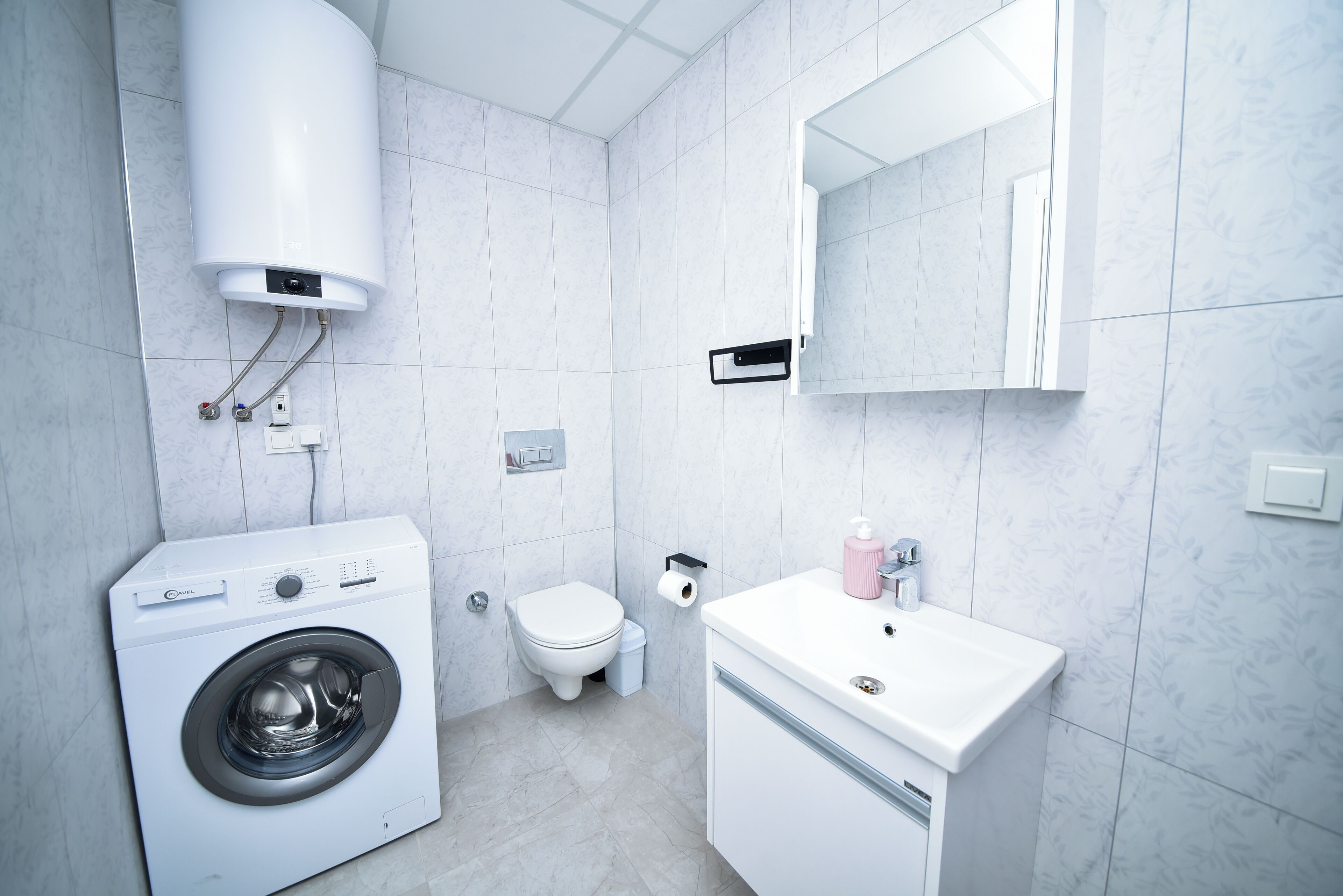 Un baño moderno con lavadora integrada, inodoro y lavabo.