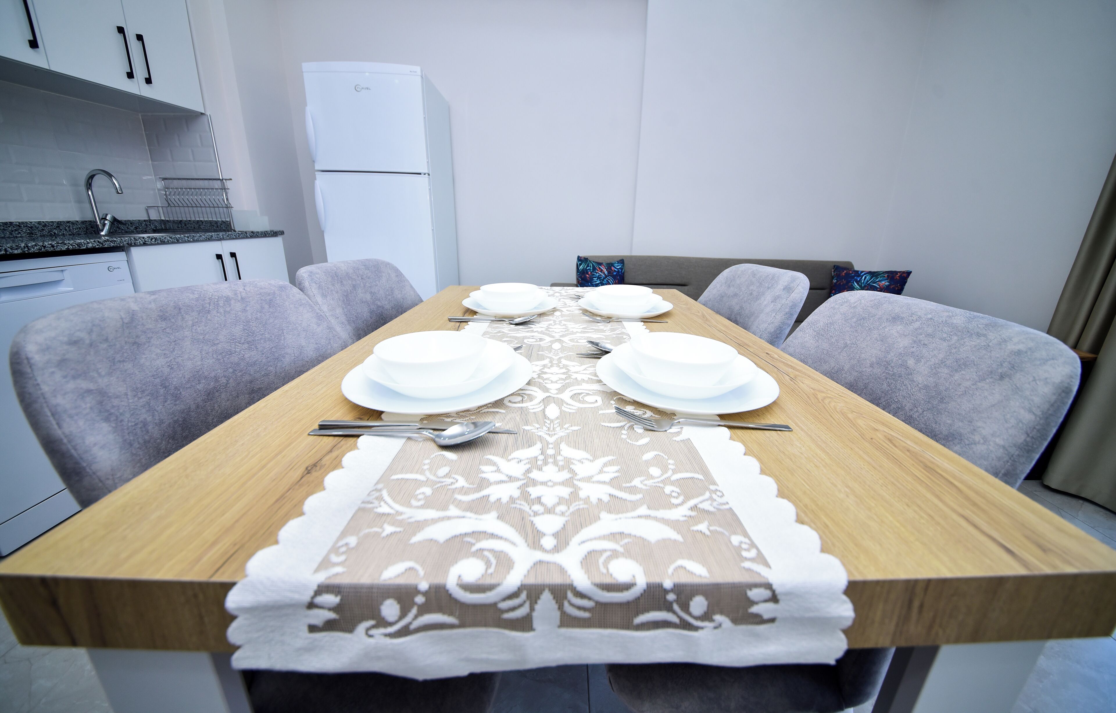 A dining table set with plates, cutlery, and a decorative table runner.