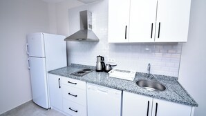 A modern kitchen with white cabinetry, a built-in dishwasher, a stainless steel range hood, and a granite countertop. - Alkan Apart (Demre)
