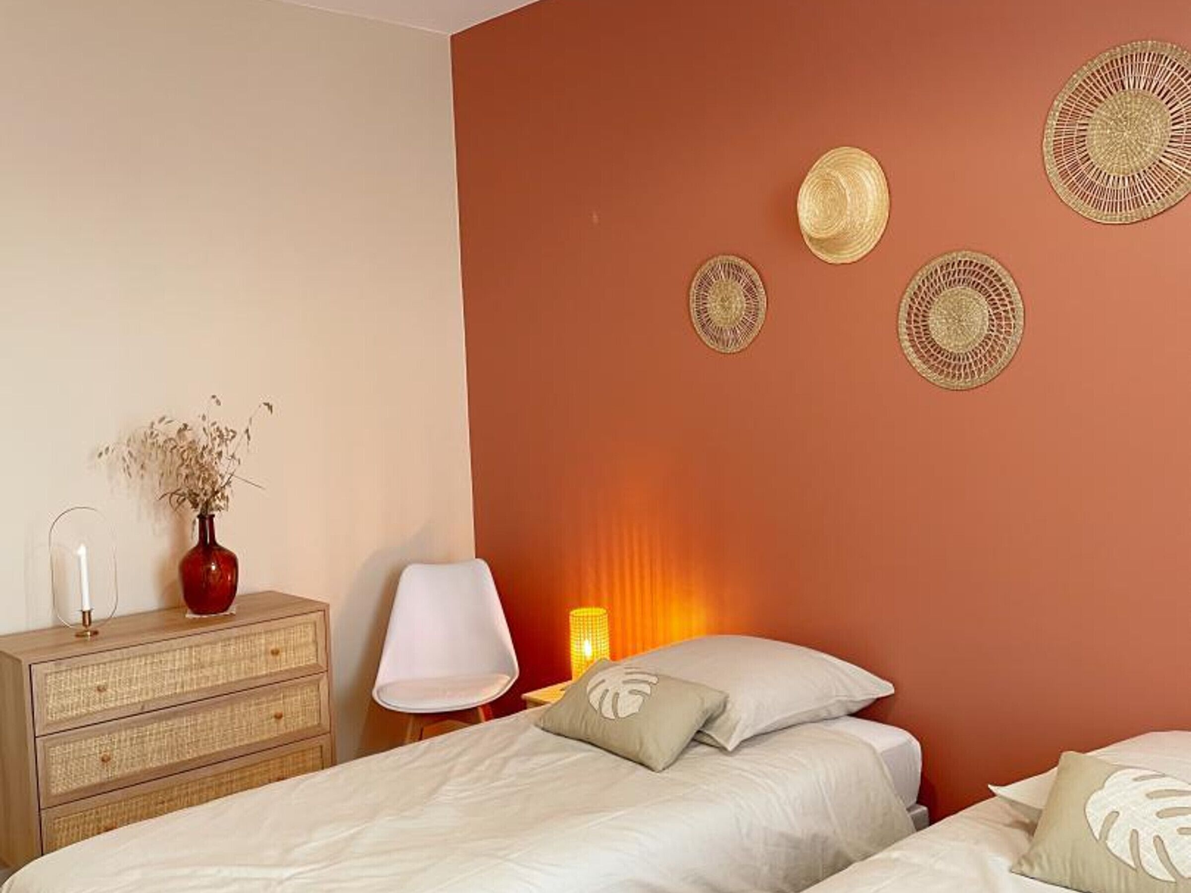 A bedroom with a bed, a dresser, a lamp, and wall decorations.