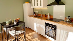 Une cuisine de taille réduite avec des meubles blancs, une cuisinière noire et un plan de travail en bois.