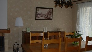 Un coin repas avec une table et des chaises en bois, un tableau encadré au mur et un luminaire suspendu.