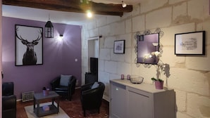 A living room with a purple wall, a fireplace, a TV, and a cabinet with a mirror and flowers.