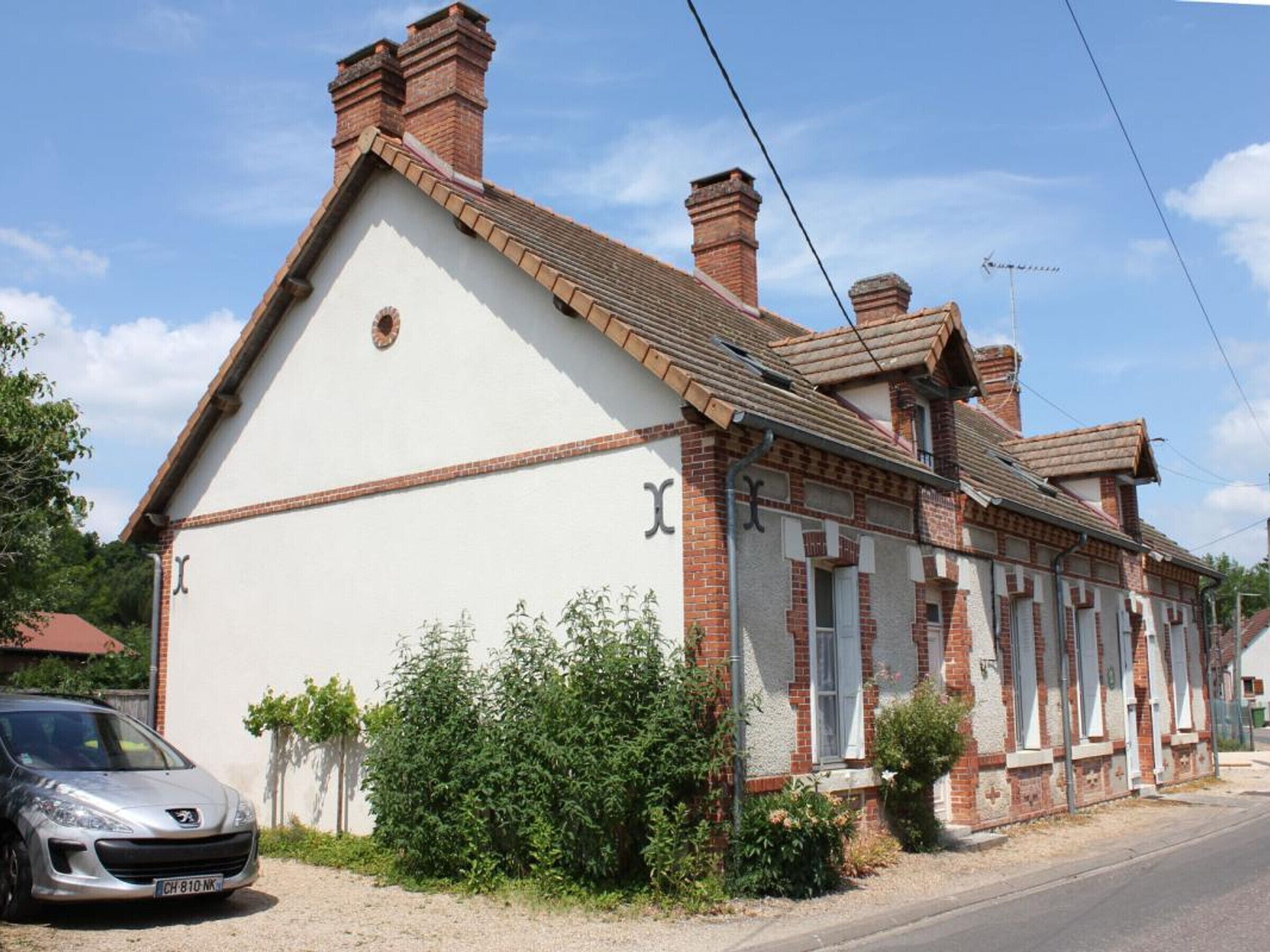 A two-story house with a white facade and red brick chimneys.