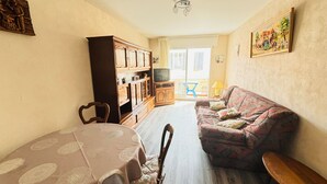 A living room with a dining table, sofa, and a TV on a cabinet.