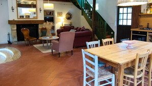 Un salon chaleureux avec une cheminée, un escalier et un coin repas.