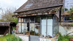 Une maison traditionnelle dotée d’une véranda, de murs en briques et d’un toit en pente.
