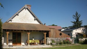 A traditional house with a pitched roof, a wooden porch, and a small garden area. - Charming cottage with garden, pets allowed (Fresnes)