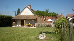 A house with a well-maintained lawn, a wooden porch, and a small garden area. - Charming cottage with garden, pets allowed (Fresnes)