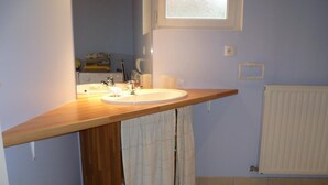 Un baño con tocador de madera, lavamanos, inodoro y ventana.