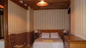 Un dormitorio con una cama de madera, dos mesitas de noche con lámparas, una silla de madera y un aparador de madera.