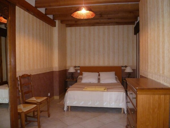 A bedroom with a wooden bed, two bedside tables with lamps, a wooden chair, and a wooden dresser.