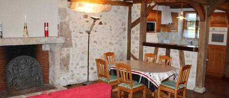 Un comedor rústico con chimenea de piedra, sillas de madera y un sofá rojo.