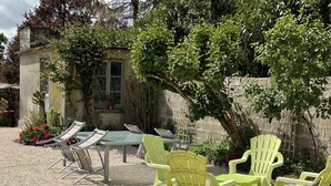 A patio with a table and chairs, surrounded by a gravel area and greenery.