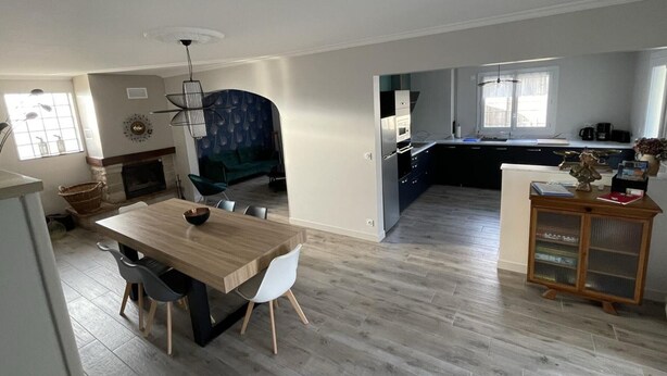 A modern kitchen with a dining area, a built-in oven, and a large window.