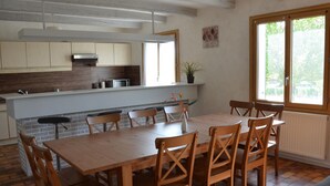 A modern kitchen with a central island, wooden dining table, and chairs. There is a window with a view of greenery outside. - Spacious house with garden, terrace, and leisure facilities in Pouillé (Pouillé)