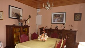 A dining room with a table set for four, surrounded by wooden chairs. There is a chandelier above the table, and the walls are adorned with framed pictures. - Charming Cottage with Private Garden, Terrace & Garage near Loire Castles (Huisseau-sur-Cosson)