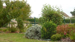 A garden with various shrubs and a fenced area. - Charming Cottage with Private Garden, Terrace & Garage near Loire Castles (Huisseau-sur-Cosson)