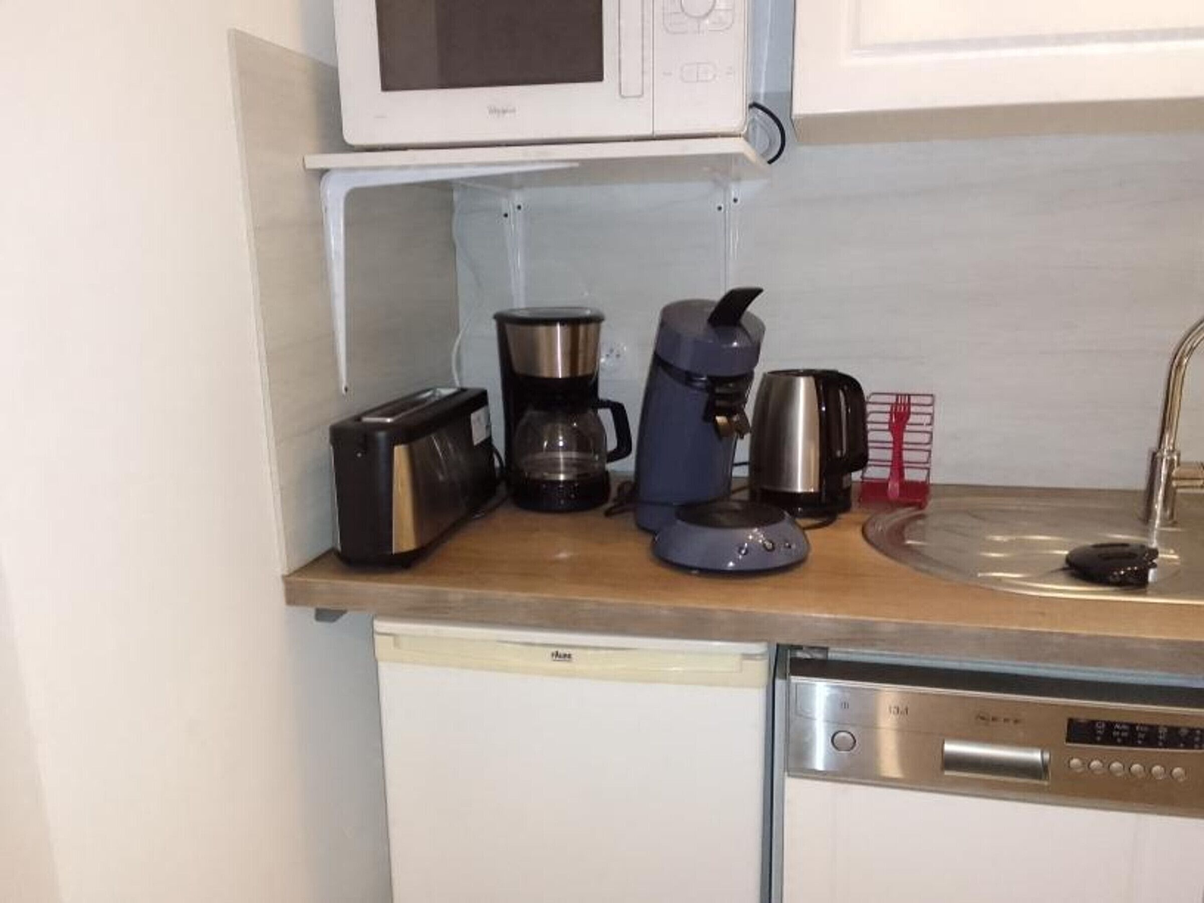 A kitchen with a microwave, toaster, coffee maker, and dishwasher.