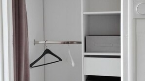 Een witte kast met planken en een kledingroede.