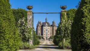 A historic building with a symmetrical facade, a central entrance, and a traditional gate with urns. - Single-story house with private garden, pets allowed (Villeherviers)
