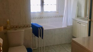 A bathroom with a toilet, a sink, a bathtub, and a window with curtains. - Single-story house with private garden, pets allowed (Villeherviers)
