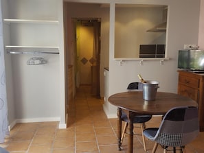 Un comedor con una mesa redonda, dos sillas, un armario y un televisor sobre un mueble de madera.