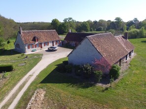 Et landhus med grusvej og en bil foran.
