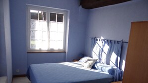 Un dormitorio con una cama individual, una ventana con cortinas y un armario de madera.