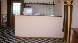 Una cocina con un refrigerador, un reloj y un piso a cuadros.