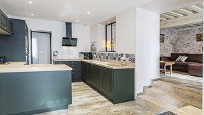 A modern kitchen with dark cabinetry, a central island, and a black range hood. - Charming Cottage in Cheverny with Garden and Garden Furniture (Cheverny)