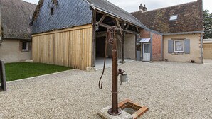 A rustic building with a sloped roof, wooden siding, and a gravel courtyard. - Charming Cottage in Cheverny with Garden and Garden Furniture (Cheverny)