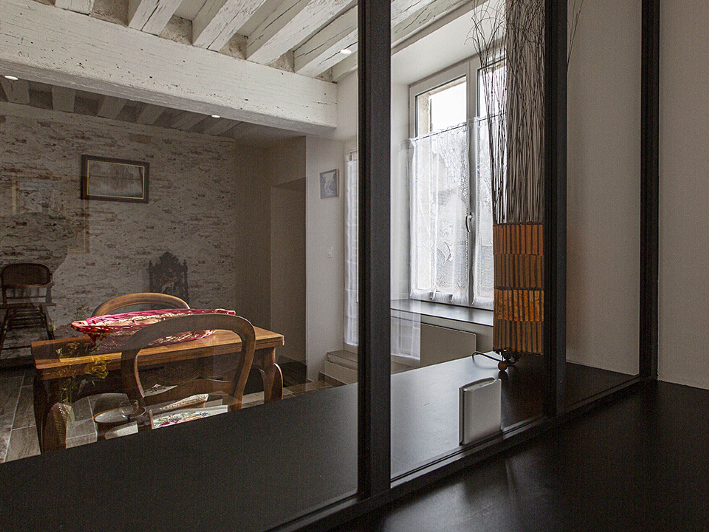 Un coin repas avec une table et des chaises en bois, un mur en briques blanches et une fenêtre avec des rideaux.