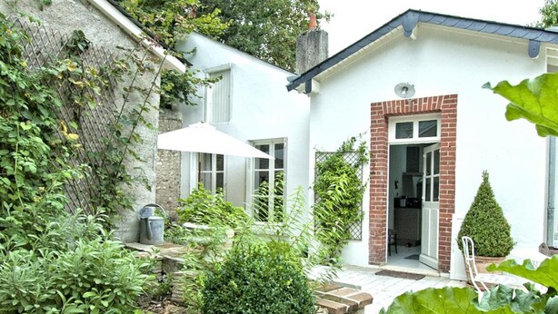 Een klein huis met een tuin, terras en een entree van baksteen.