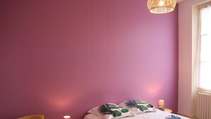 A bedroom with a bed, a chair, a lamp, and a window.
