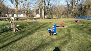 A playground with swings, a slide, and a merry-go-round.