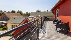 Un balcon avec une balustrade en métal, deux chaises et une petite table.
