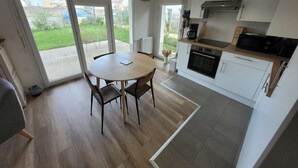 Eine moderne Küche mit Essbereich, großen Fenstern und Blick ins Freie.