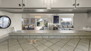 A spacious living area with a large window, a chandelier, and a sofa. - Ground Floor Condo Nestled Against The Dunes! (St. Augustine)